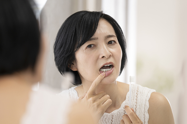 歯のトラブルを鏡で確認する女性
