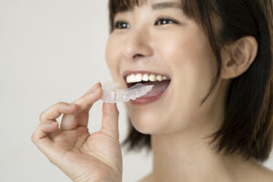 矯正用のマウスピースでホームホワイトニングをする女性