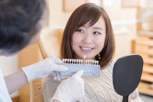 歯の色見本を試しながら笑う女性