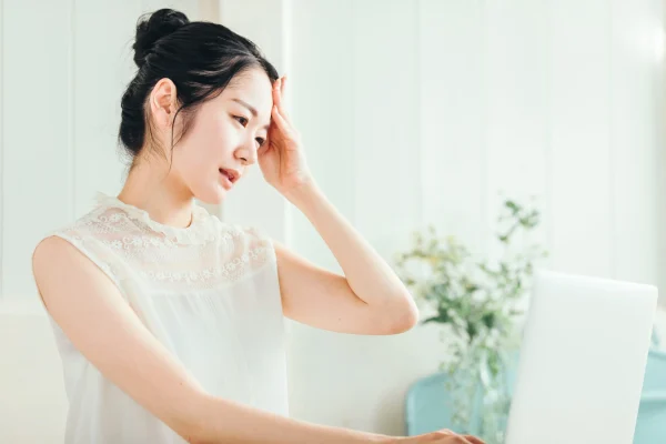 頭をかかえる白い服を着た女性