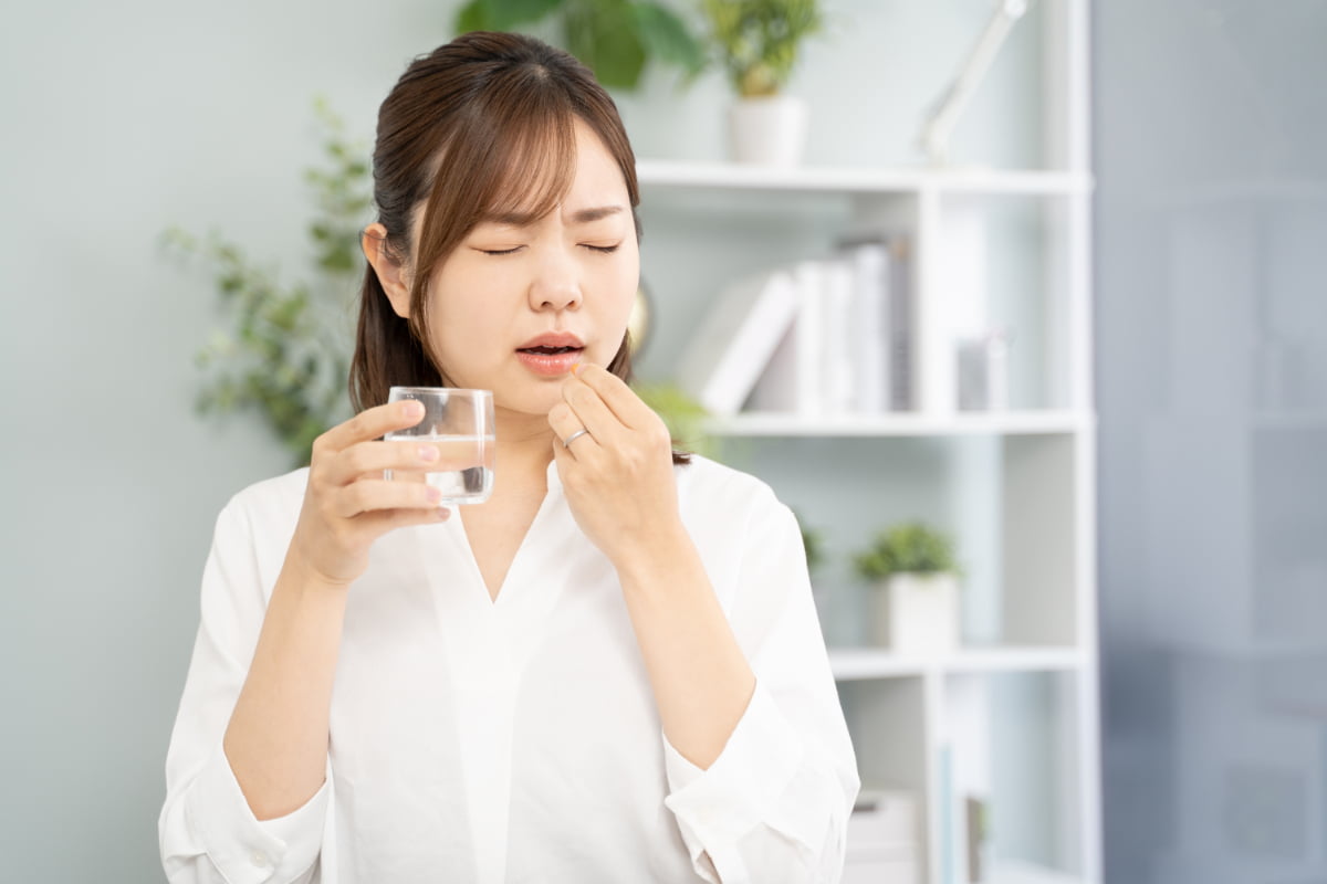 インプラント治療後に痛み止めを飲む女性