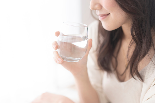 グラスに入った水を飲む日本人女性