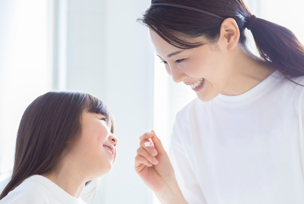 乳歯が虫歯になるのを防ぐため仕上げ磨きをする親子