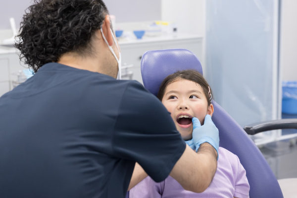 プレオルソ治療が適応か判断するために子どもの口腔内を診察する歯科医師