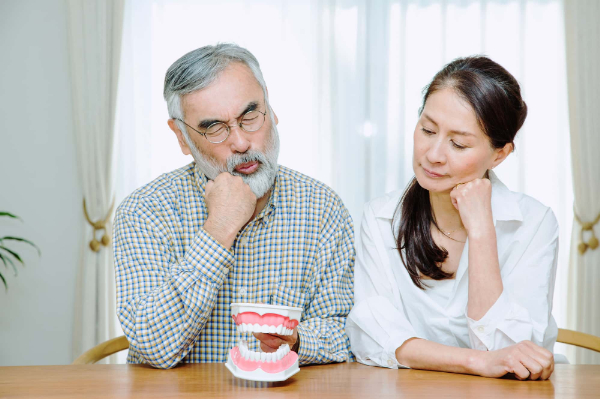 入れ歯が外れる原因について考える男女