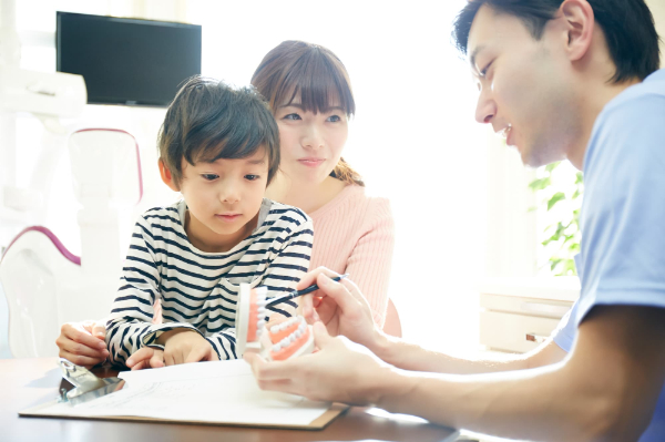 インビザライン・ファーストの治療について歯科医に相談する親子