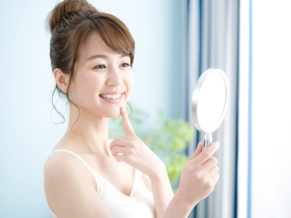 手鏡で自分の歯を見て笑う女性