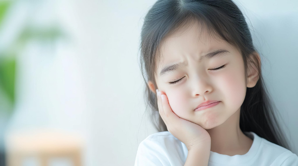 歯肉炎が痛くて頬をおさえる女の子