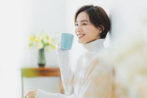 マグカップ片手にリラックスする白いニットを着た女性