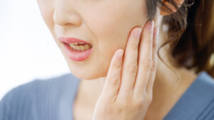 噛み合わせに違和感を感じ顎を押さえる女性