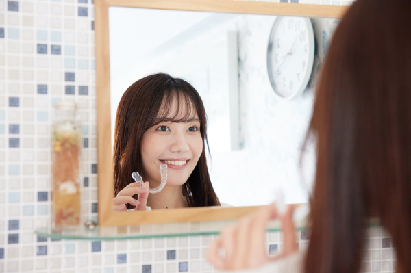 時計を確認しマウスピースを装着する女性