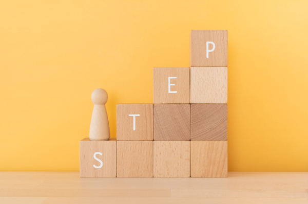 STEPと書かれた積み木を登る木の人形