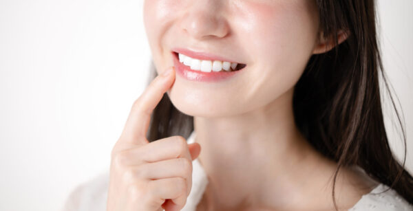 ラミネートベニアで綺麗になった前歯を指差す女性