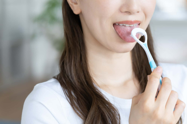 付着した舌苔を専用ブラシで除去する女性