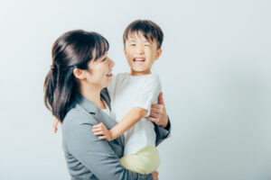 子どもを抱きかかえて笑顔の母親