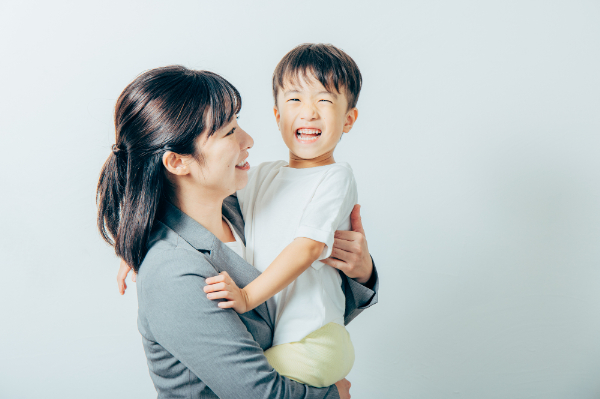 子どもを抱きかかえて笑顔の母親