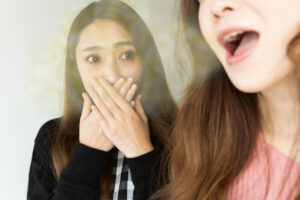 親知らずの周囲の腫れを放置して口臭が発生してしまった女性に友人が驚いているイメージ