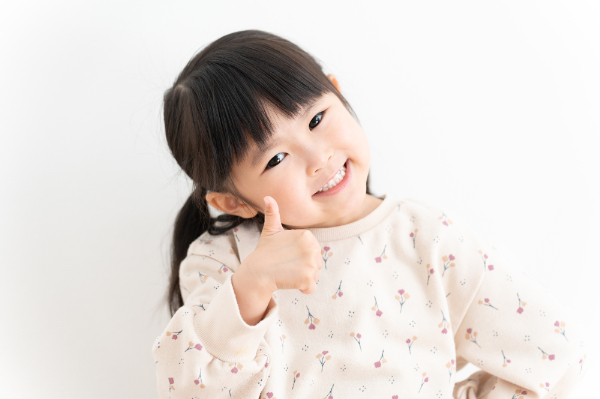 虫歯ゼロでグーサインを見せる女の子