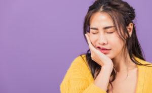 顎関節症で痛む顎をおさえる女性