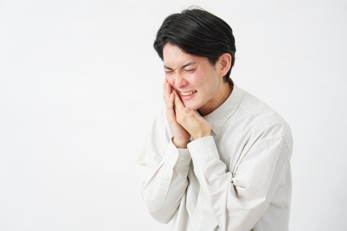 親知らずが生え始めるサインとして歯茎の近くが痛む男性