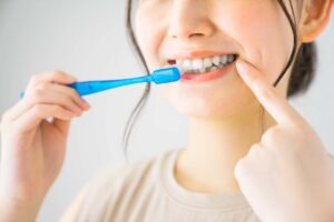 歯みがきをしている口を指さす女性