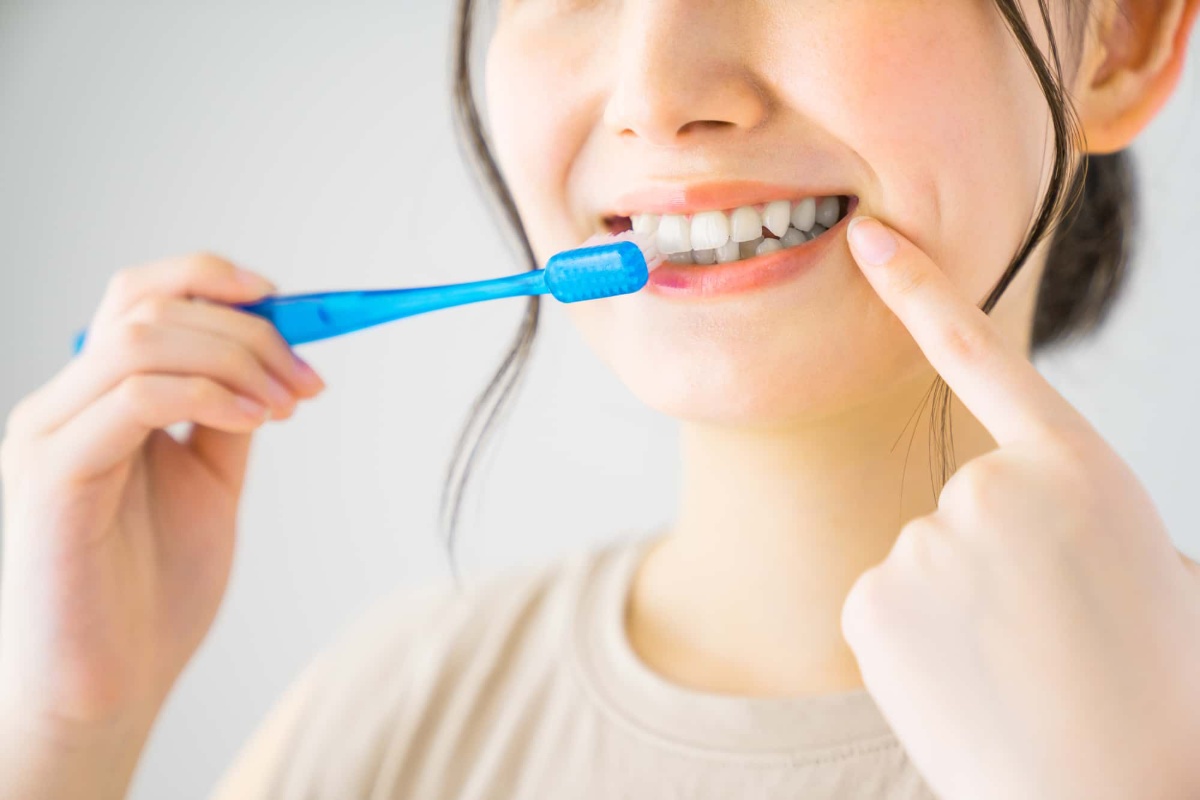 歯みがきをしている口を指さす女性