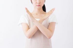 体の前でバツを作る女性