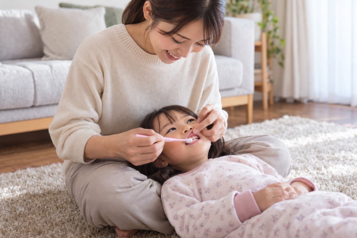 仰向けの体勢で仕上げ磨きをする様子