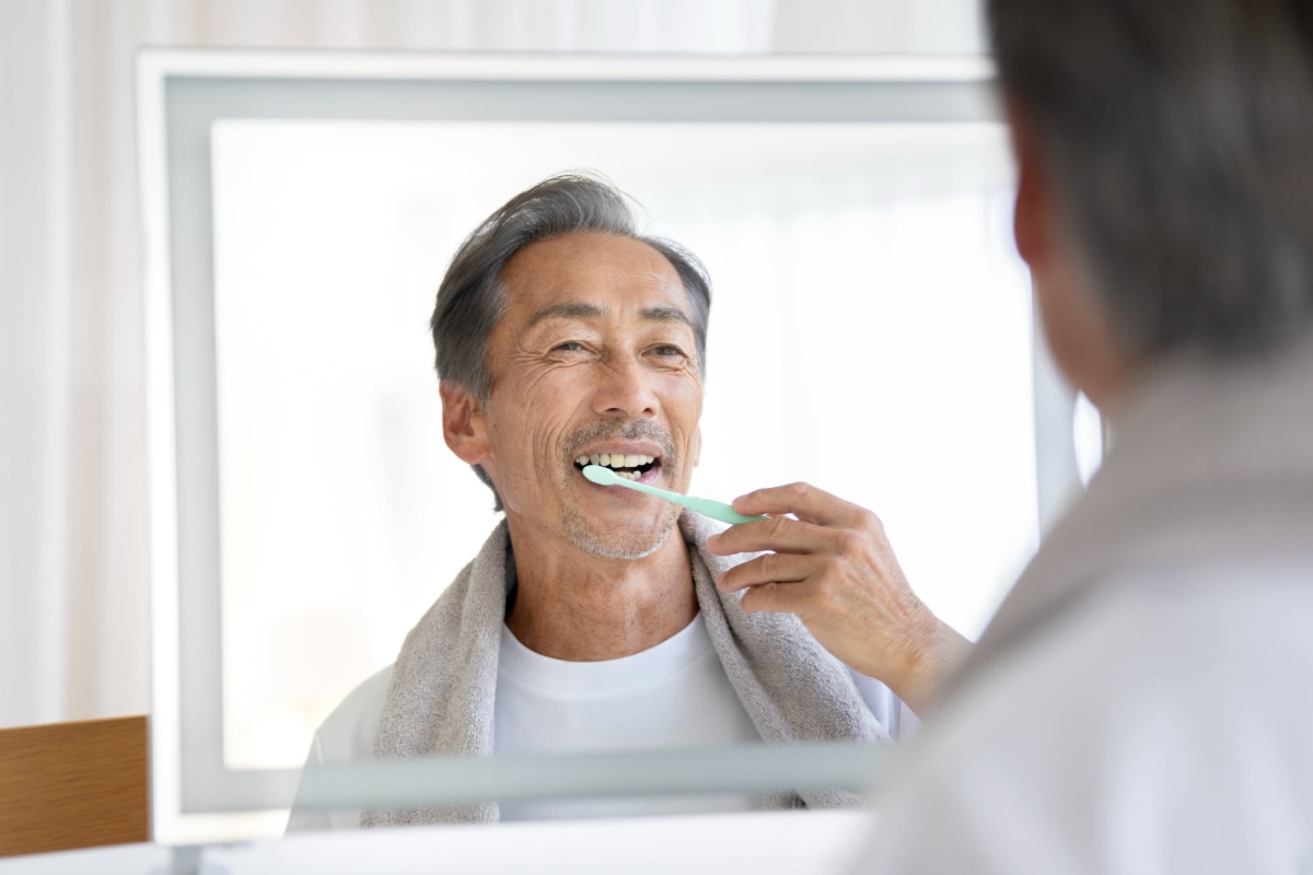 鏡を見ながら丁寧に歯みがきをしているミドル男性
