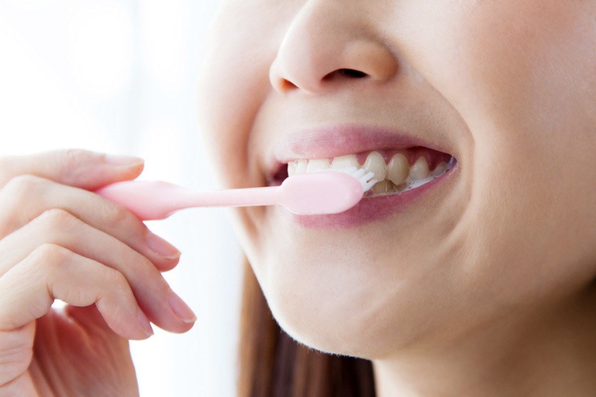 ラミネートべニアと歯茎の境目を丁寧に歯みがきする女性の口元
